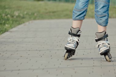 Koruyucu ekipman ve patenler içinde küçük bir çocuk parkta yürüyüş yolunda duruyor, alçak açılı.