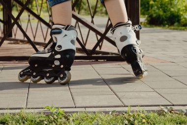 Koruyucu ekipman ve patenler içinde küçük bir çocuk parkta yürüyüş yolunda duruyor, alçak açılı.