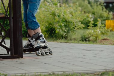 Koruyucu ekipman ve patenler içinde küçük bir çocuk parkta yürüyüş yolunda duruyor, alçak açılı.