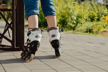 Koruyucu ekipman ve patenler içinde küçük bir çocuk parkta yürüyüş yolunda duruyor, alçak açılı.