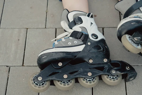 Koruyucu ekipman ve patenler içinde küçük bir çocuk parkta yürüyüş yolunda duruyor, alçak açılı.