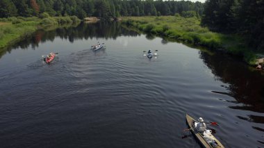 İnsansız hava aracı bakış açısı suda yüzen bir kano sürücüsü. Göl kenarındaki kano grubunun hava aracı görüntüsü. Nehir yatağı boyunca kano ve kano gezisi. Rafting. Bir Tekne İzleniyor