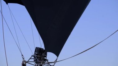 Bir adam balon festivalinde büyük bir balon kaldırıyor. Sıcak hava balonlarını patlatmak. Alevler yükseliyor ve sıcak hava balonunu şişiriyor. Pilot sıcak hava balonundaki alevi ayarlıyor. Sıcak hava balonu şişiyor. Sıcak Hava Balonlarını Patlatan.