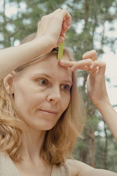 Young woman with green tapes on face. Face aesthetic taping. Attractive young woman with kinesiology tapes on forehead. Beautiful Woman With Kinesiology Facelift Tapes