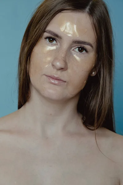 眼パッチの下に適用する女性 暗い円とパフのための目のマスク 彼女の目の下に黄金のコラーゲンパッチを適用するかなりの女の子 女性の顔の治療 — ストック写真