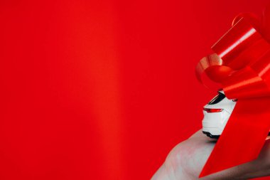 Noel konsepti için istenen hediye. 23 Ağustos 2021 'de Rusya' nın Ryazan kentinde kırmızı arka planda bulunan kırmızı kurdeleyle sarılı küçük ve lüks bir oyuncağın yakın fotoğrafını çek.