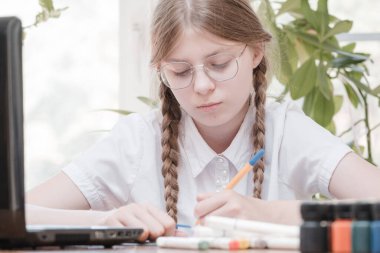 Evdeki online dersi sırasında ödev okuyan güzel bir liseli kız karantina sırasındaki sosyal mesafe, kendini izole etme, online eğitim konsepti, evde eğitim veren biri. Uzaklık öğrenimi çevrimiçi eğitim