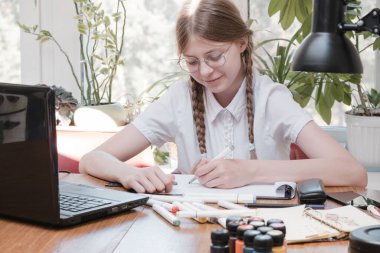 Evdeki online dersi sırasında ödev okuyan güzel bir liseli kız karantina sırasındaki sosyal mesafe, kendini izole etme, online eğitim konsepti, evde eğitim veren biri. Uzaklık öğrenimi çevrimiçi eğitim