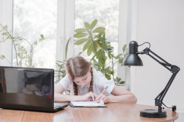 Ödevinde dizüstü bilgisayar kullanarak kendini izole eden bir öğrenci. Dijital tablet kullanarak internetten bilgi toplayan bir kız. Sosyal uzaklık, E-öğrenim çevrimiçi eğitim