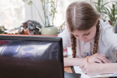 Evdeki online dersi sırasında ödev okuyan güzel bir liseli kız karantina sırasındaki sosyal mesafe, kendini izole etme, online eğitim konsepti, evde eğitim veren biri. Uzaklık öğrenimi çevrimiçi eğitim