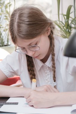 Okulda okuyan küçük bir kız öğrenci. Ev hobisi. Evde resim yapan gülümseyen kız çocuğu. Öğretmenler tarafından eğitilmek ve ailelerle evde çalışmak. Ödev yapan genç kız..