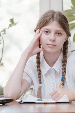 Okulda okuyan küçük bir kız öğrenci. Ev hobisi. Evde resim yapan gülümseyen kız çocuğu. Öğretmenler tarafından eğitilmek ve ailelerle evde çalışmak. Ödev yapan genç kız..