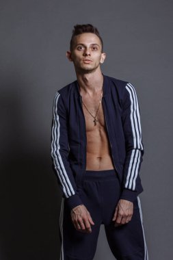 Gri stüdyo arka planında eşofman giyen mutlu sporcunun ön manzara portresi..