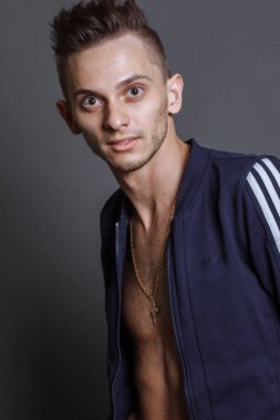 Gri stüdyo arka planında eşofman giyen mutlu sporcunun ön manzara portresi..