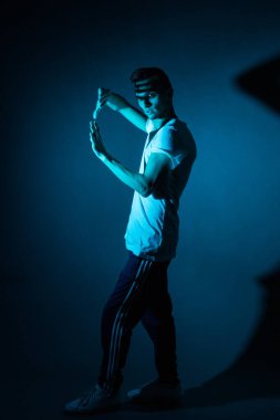 Gri stüdyo arka planında eşofman giyen ön manzara sporcusu. Beyaz tişörtle egzersiz yaptıktan sonra bir sporcunun portresi