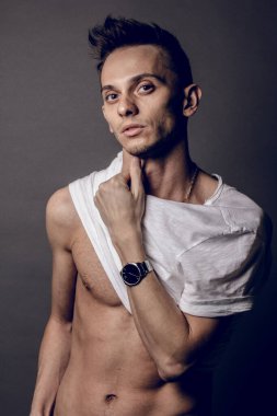 Gri stüdyo arka planında eşofman giyen ön manzara sporcusu. Beyaz tişörtle egzersiz yaptıktan sonra bir sporcunun portresi