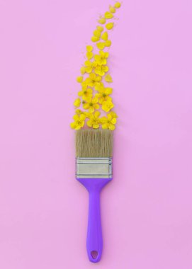 Pembe arka planda boya fırçası ve sarı kır çiçekleri olan yaratıcı bir düzen. Çiçekli fırça boyaları. Boşluğu kopyala