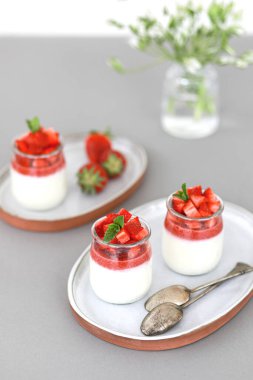 İtalyan tatlı panna cotta ile meyveli jöle ve gri arka planda taze çilek parçaları. Boşluğu kopyala