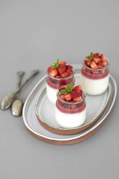 Dessert italien panna cotta avec gelée de fruits et des morceaux frais de fraises sur fond gris. Espace de copie — Photo