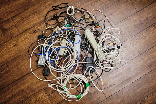 A tangled tangle of unnecessary wires lies on the floor