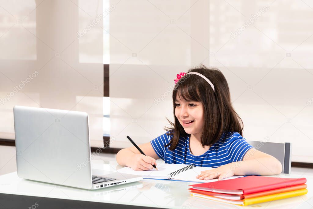 A little girl of 6 years old from first grade old homeschooling through video conference.