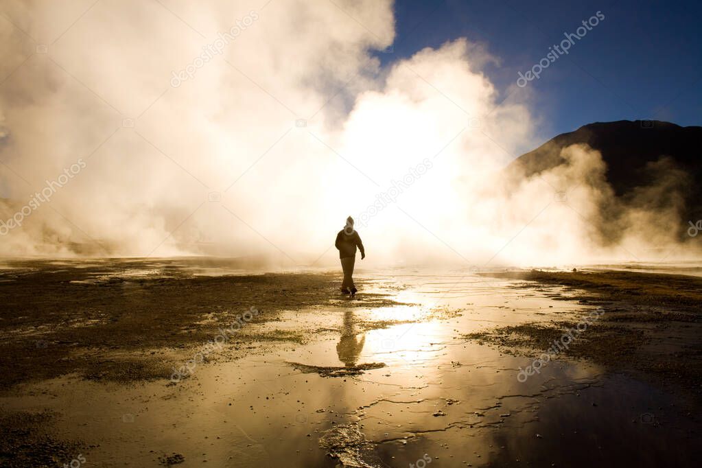 Sunrise at El Tatio Geysers at an altitude of 4300m, with a tourist walking between the fumaroles, Atacama desert, Antofagasta Region, Chile, South America