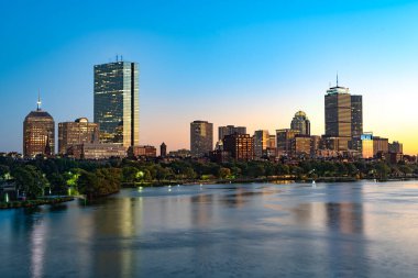 Alacakaranlıkta Charles Nehri 'nin karşısındaki Back Bay' in Boston şehir manzarası göze çarpan binaları gösteriyor..