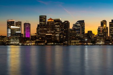 Alacakaranlıktaki Boston şehir manzarası göz kamaştırıcı, renkli gökyüzüne karşı aydınlatılmış gökdelenleri gösteriyor..