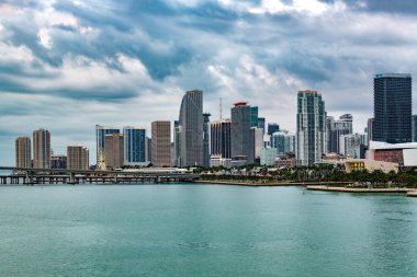 Miami, Florida, ABD - 09 Aralık 2025: Modern Miami şehir merkezi gökyüzü bulutlu bir günde Biscayne Körfezi 'nin turkuaz sularından dramatik bir şekilde yükseliyor.