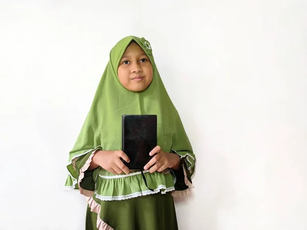 印度尼西亚穆斯林女孩穿着绿色衣服 站在白色背景面前 手持和阅读 古兰经 — 图库照片