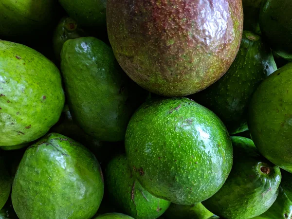 Bir yol kenarındaki meyve dükkanında seçici bir odak noktasıyla sergilenen bir avuç avokado 'nun yakın plan fotoğrafı.