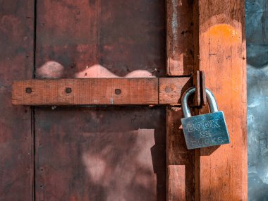 Sabahın erken saatlerinde biraz paslı bir kilitle kilitlenmiş ahşap bir kapı.