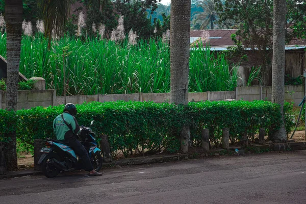 2021年4月25日インドネシア マラン 道路脇に停車してスマートフォンで注文を確認するオンラインバイクタクシーの運転手 — ストック写真