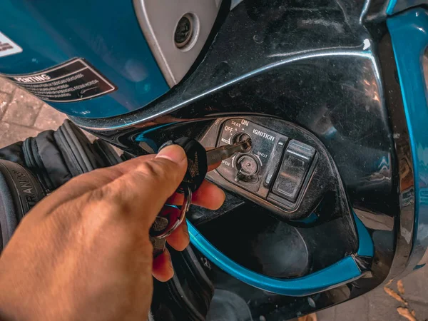Malang, Endonezya -27 Nisan 2021: Bir motosiklet sürücüsü motoru çalıştırmadan önce motor anahtarını anahtar sahibine yerleştirir