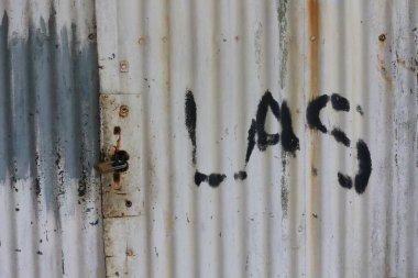 Eski yeşil ahşap kapı girişi, eski çinko duvar / grunge doku arka planı, kaynak anlamında Endonezce yazılmış.