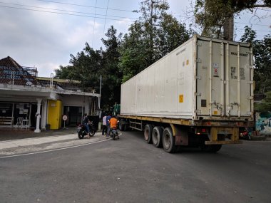 Malang, Endonezya - 28 Mayıs 2021: Malang şehrinde küçük bir yoldan geçen büyük bir konteynır trafiği tıkadı.