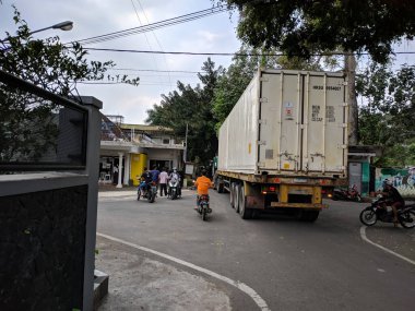 Malang, Endonezya - 28 Mayıs 2021: Malang şehrinde küçük bir yoldan geçen büyük bir konteynır trafiği tıkadı.