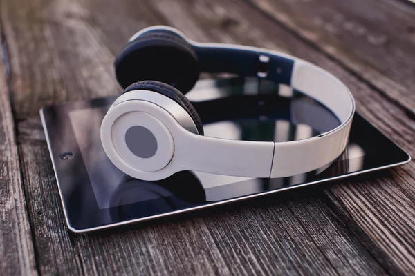 Tablet ordenador con auriculares sobre fondo de madera —  Fotos de Stock