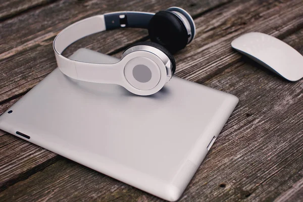 Tablet computer with headphones and mouse against wooden backgro — Stock Photo, Image