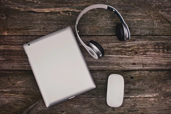 Tablet met hoofdtelefoons en muis op een houten achtergrond — Stockfoto