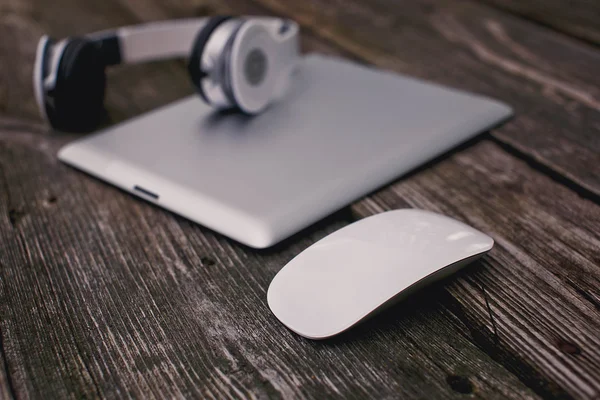 Tablet with headphones and mouse on a wooden background — Stock Photo, Image