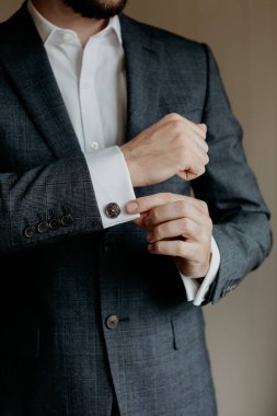 Takım elbiseli adam, beyaz gömleğini kol düğmeleriyle tut..