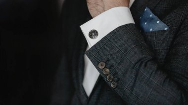 Eller kol düğmesi takar. Yakından..