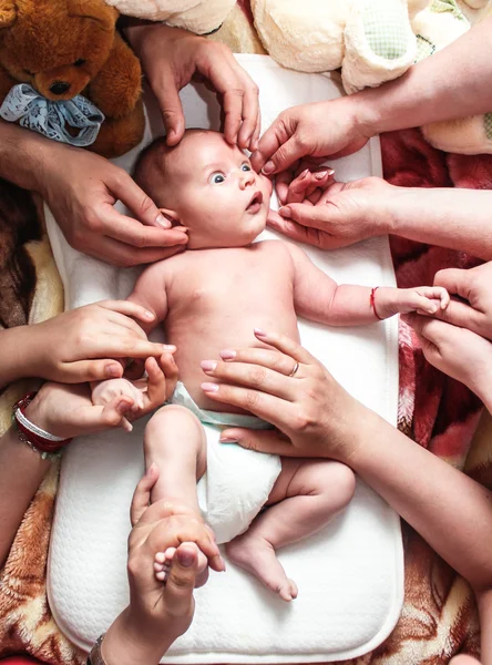 Bebé recién nacido con grandes ojos siendo tocado por manos de muchas familias Fotos De Stock Sin Royalties Gratis