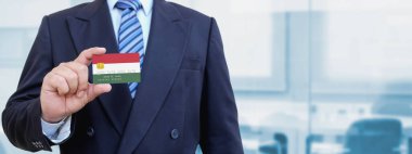 Macaristan 'ın baskılı bayrağıyla plastik kredi kartı tutan işadamının kesilmiş görüntüsü. Arkaplan bulanık.