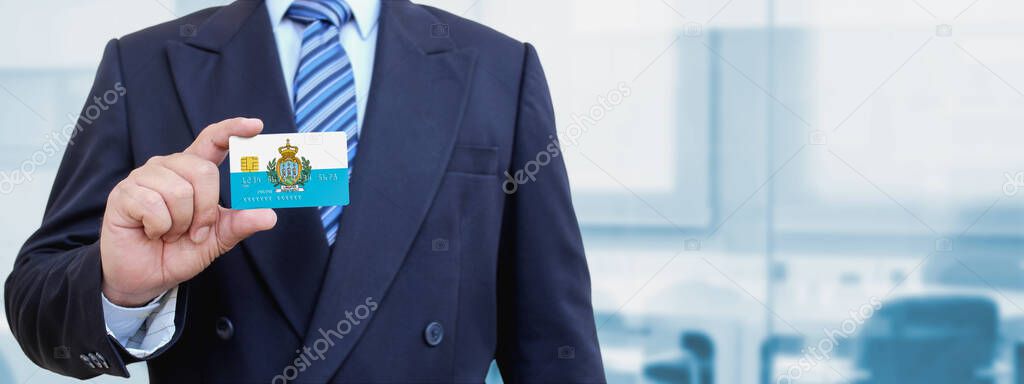 Cropped image of businessman holding plastic credit card with San Marino. Background blurred.