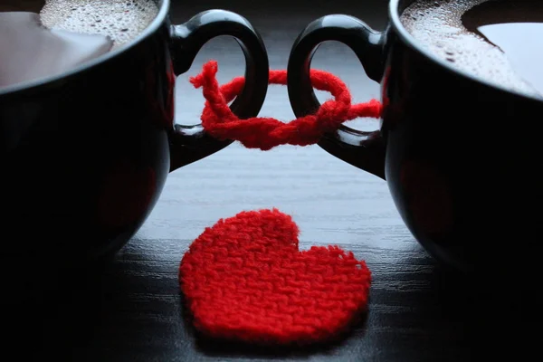 Two cups of coffee and red heart on the table