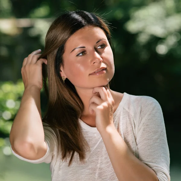 Beautiful young woman among green trees — Stock Photo, Image