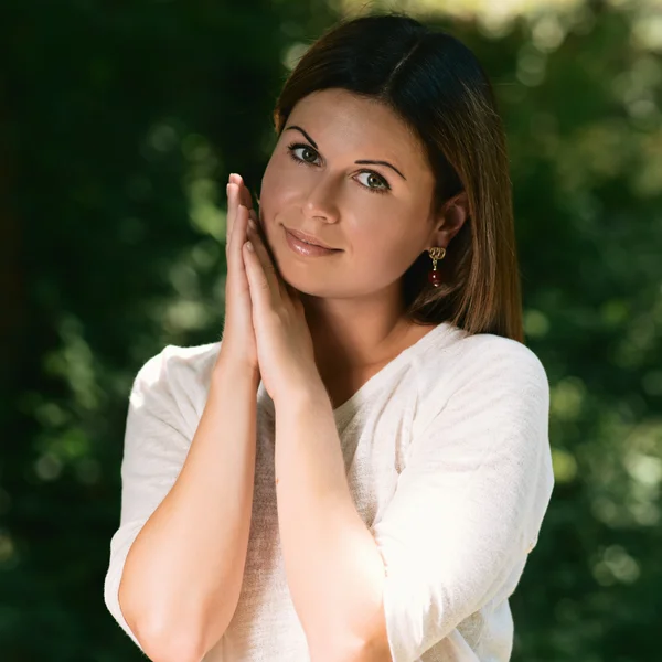 Beautiful young woman among green trees — Stock Photo, Image