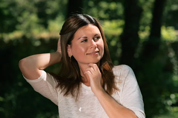 Beautiful young woman among green trees — Stock Photo, Image